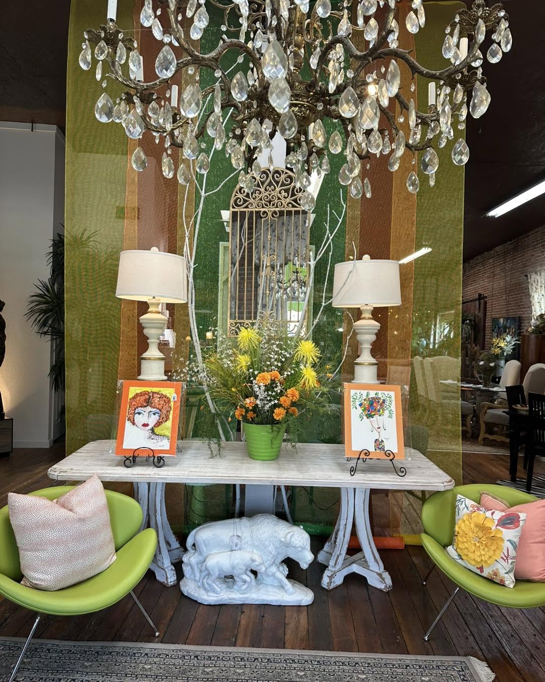 Emerald green chairs beneath a brass chandelier